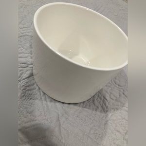 Round white jar with open whole at bottom.